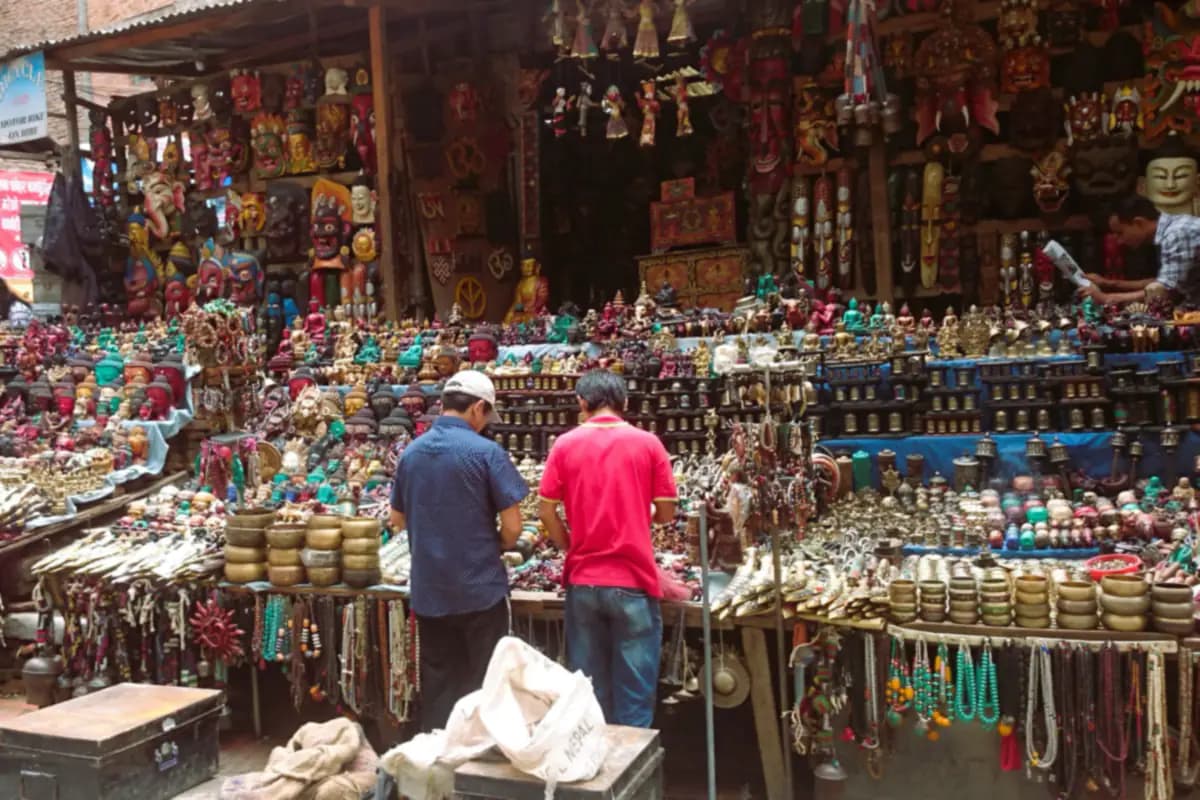 A souvenir stall in Thamel, Kathmandu, crowded with carved masks, small statues, brass bowls and bead necklaces