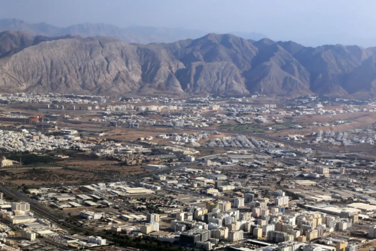 Aerial view of Muscat spreading across the plain below the bare slopes of the Hajar Mountains